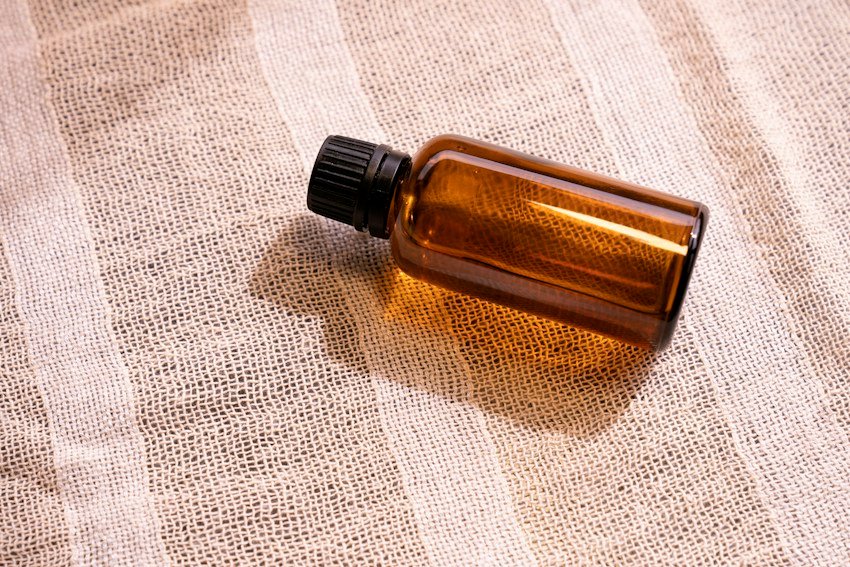 Amber essential oil bottle on natural woven fabric